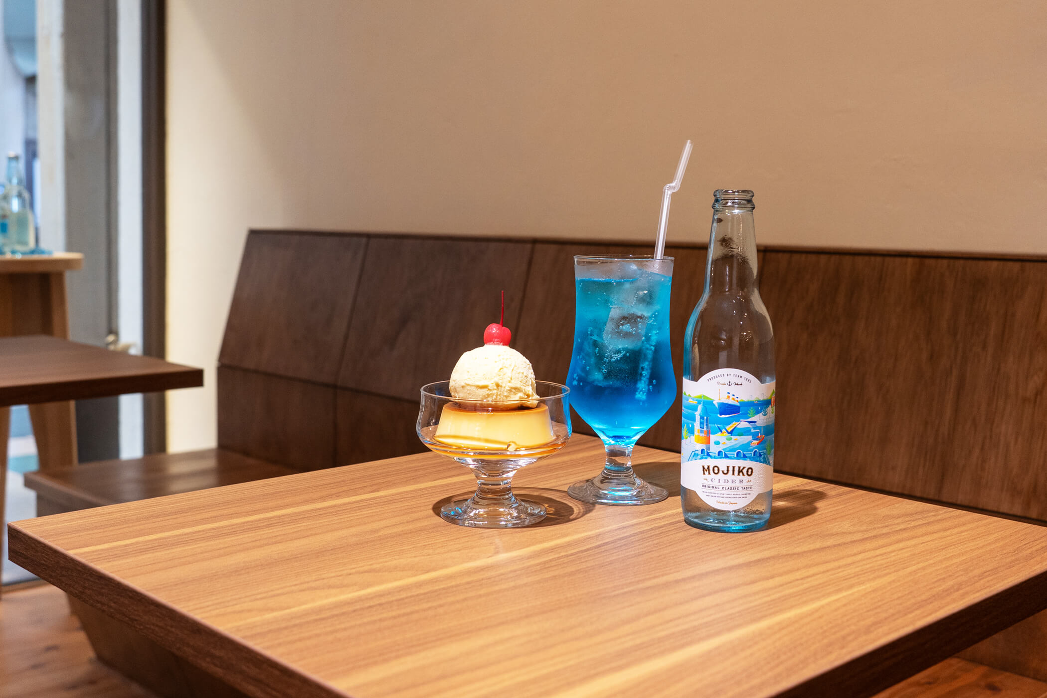 店内のテーブルに並ぶ門司港レトロプリン、門司港サイダーブルー、門司港サイダーの瓶